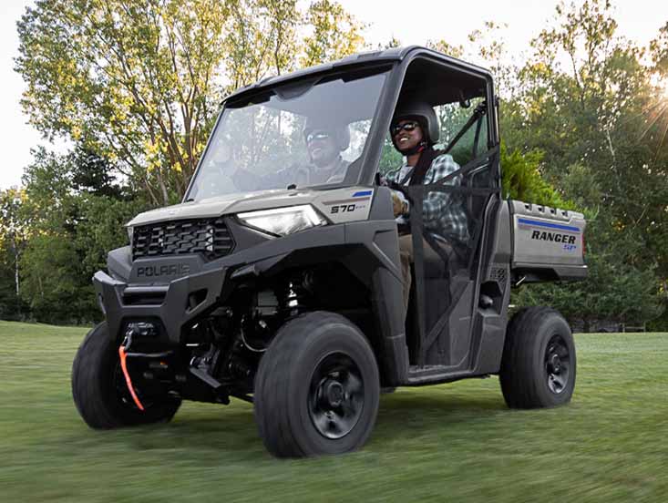 Person driving Polaris Ranger hauling items in the back of it