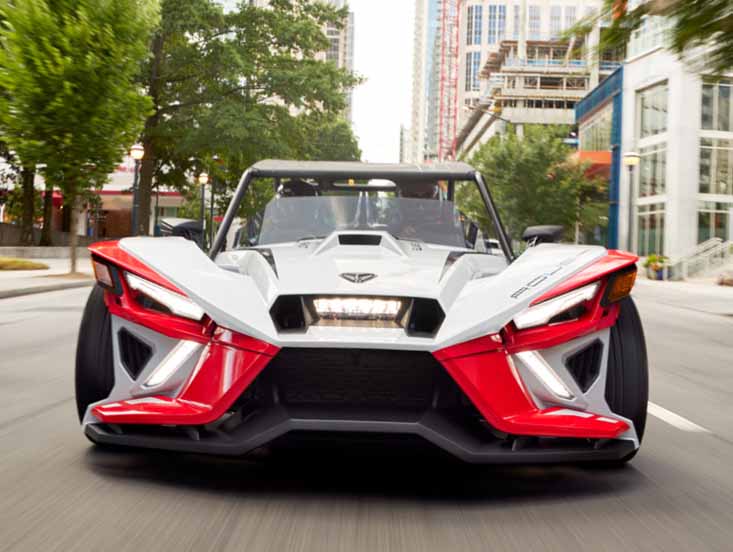 Front facing Slingshot trike driving down a paved road
