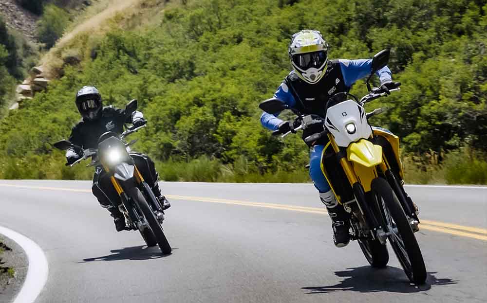 Two MX riders traveling on Suzukis riding on road