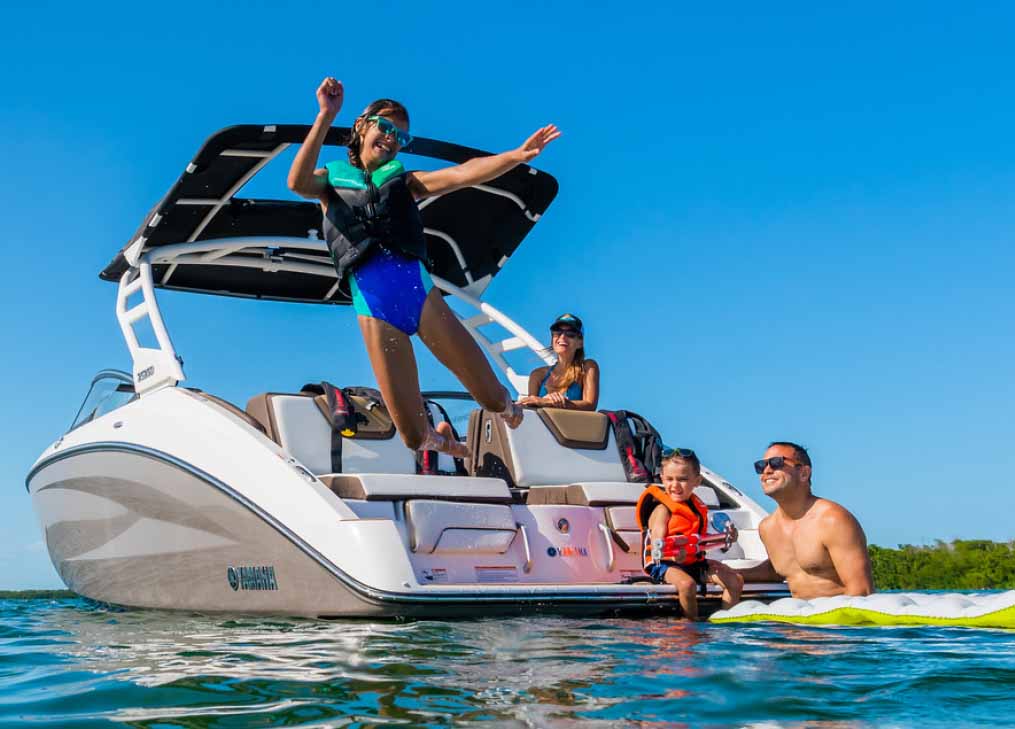Family having fun on a Yamaha jet boat with a young child jumping off the back into the water