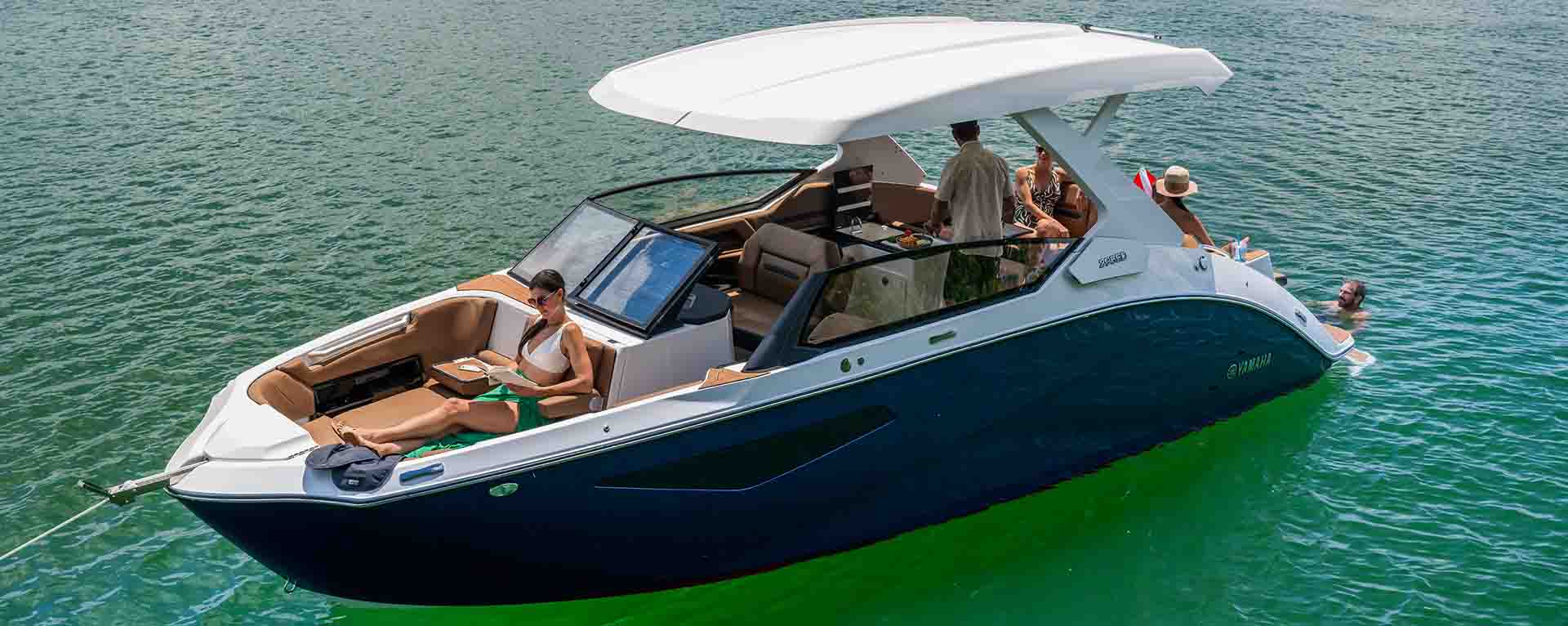 Five people enjoying drinks and conversation on the rear seats of the Yamaha 295 Series, gathered under the hardtop.