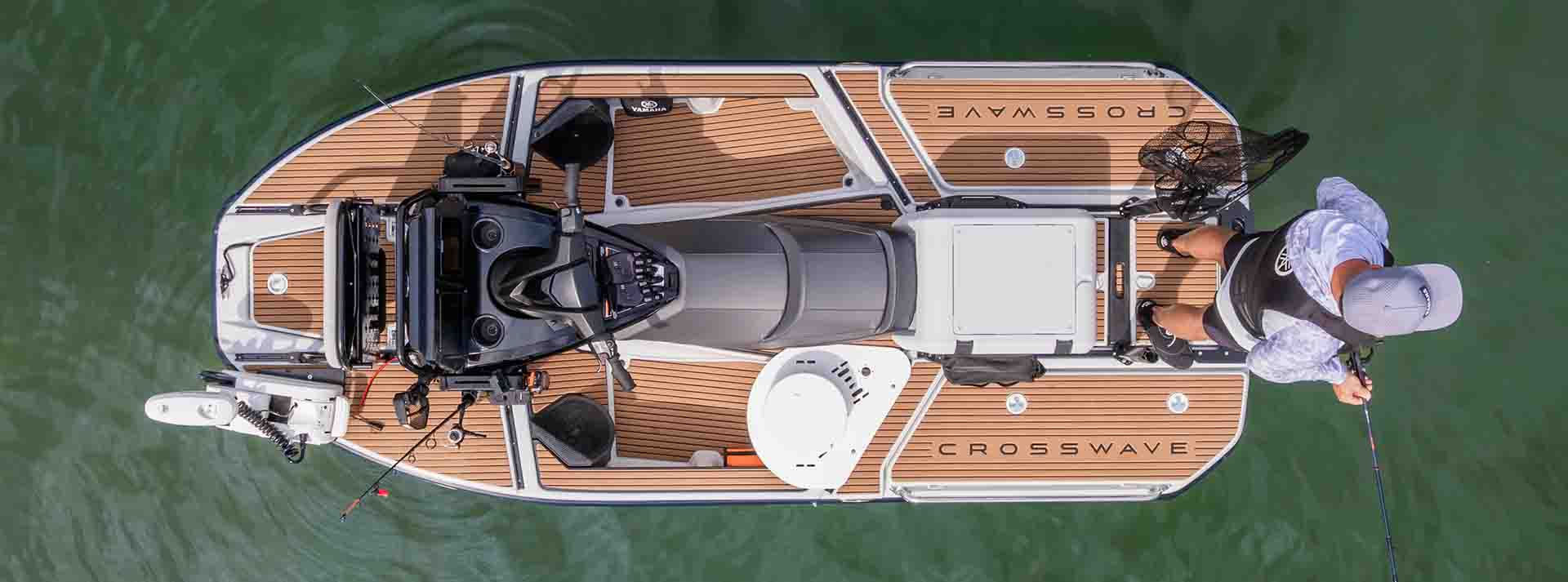 Top-down view of a Yamaha CrossWave watercraft with faux teak decking, advanced helm station, and fishing setup, highlighting spacious design and utility.