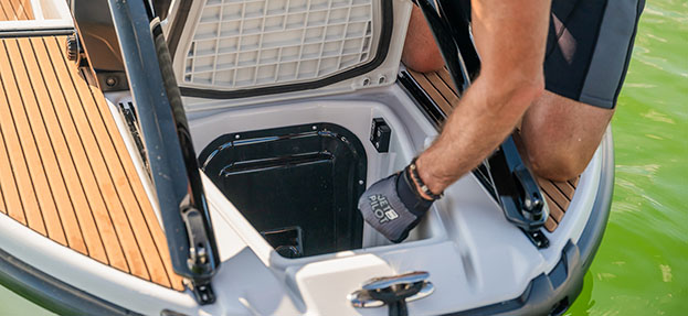 Storage compartment being accessed at the bow of the Yamaha CrossWave, highlighting gear capacity and convenience for on-water activities.